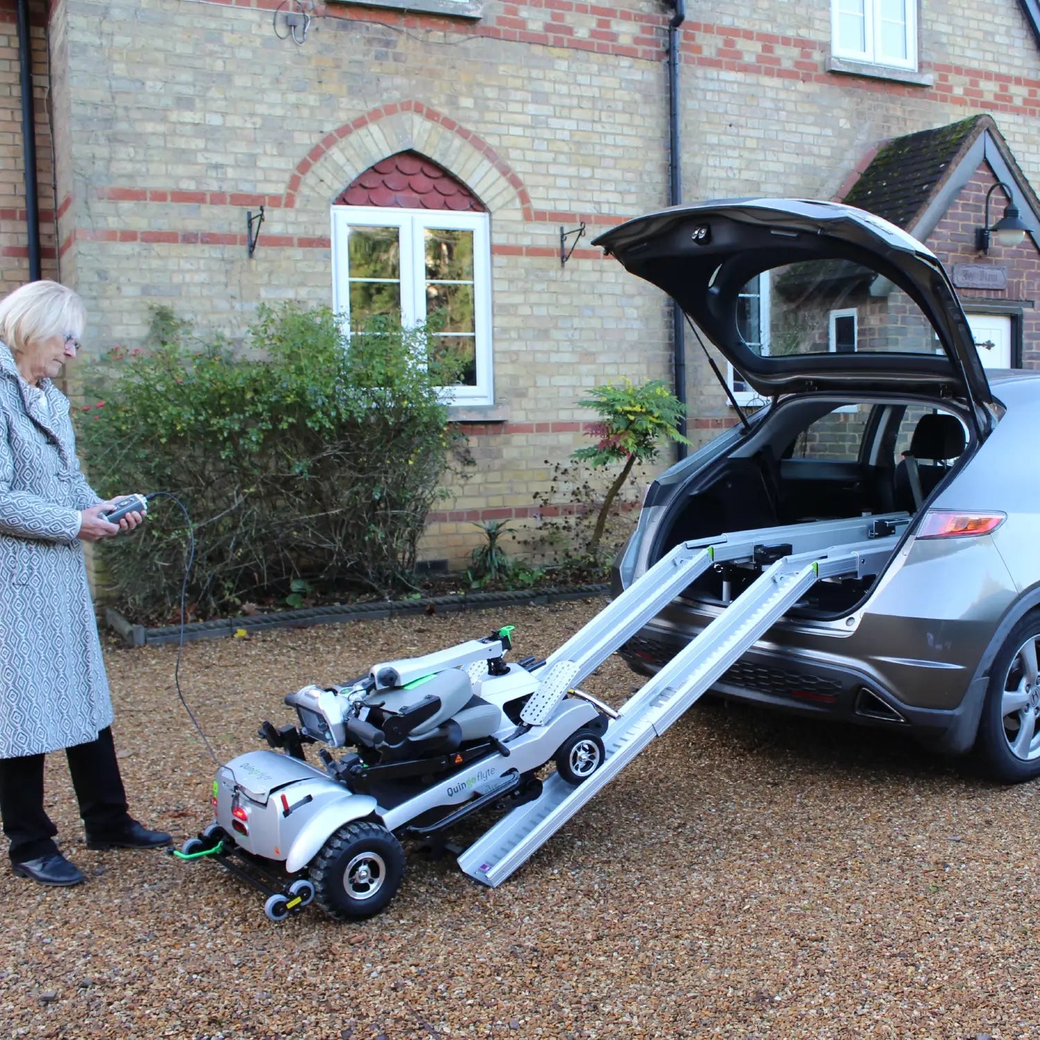 ComfyGO Quingo Flyte mobility scooter with MK2 self-loading ramp, compact design for easy outdoor transportation.